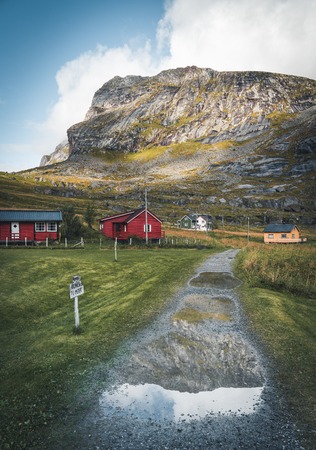 Famous tourist attraction of Reine in Lofoten, Norway with red rorbu houses, clouds, rainy day with bridge and grass and flowers.の写真素材
