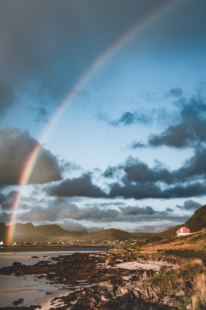 Double Rainbow over the small fishing village with blue sky and cloouds and mountains in the Lofoten Islands, Norway.の写真素材