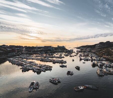 View of the port of Ilulissat Sunny day during sunset sunrise. In the foreground is a Marina with...
