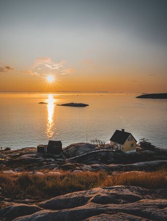 Aerial View of Arctic city of Ilulissat, Greenland during sunrise sunset. Colorful houses in the center of the town with icebergs in the background in summer on a sunny day with orange pink skyの写真素材