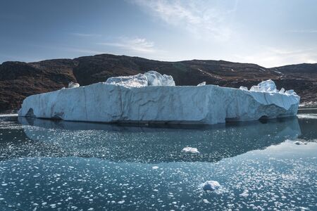 Bright sunny day in Antarctica. Full calm and reflection of icebergs in deep clear water. Travel by the ship among ices. Snow and ices of the Antarctic islands.の写真素材