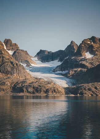 Arctic landscape in summer with high mountains and icebergs floating on the sea in Ofjords, Scoresby Sound, East Greenlandの写真素材