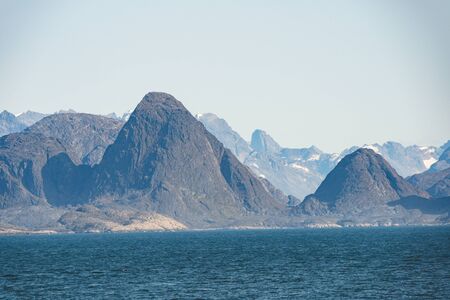 Arctic landscape in summer with high mountains and icebergs floating on the sea in Ofjords, Scoresby...