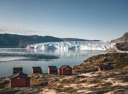 Panoramic image of Camp Eqi at Eqip Sermia Glacier in Greenland. nature landscape with lodge cabins. Midnight sun and pink sky. Tourist destination Eqi glacier in West Greenland AKA Ilulissat and Jakobshavn Glacier. Heavlly affected by Global Warming.の写真素材