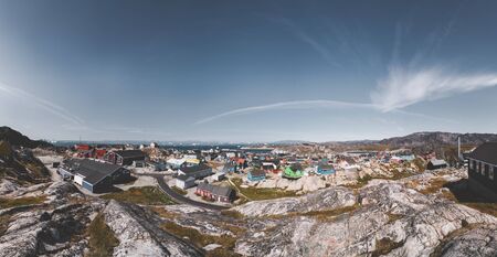 Aerial View of Arctic city of Ilulissat, Greenland. Colorful houses in the center of the town with icebergs in the background in summer on a sunny day with blue sky and cloudsの写真素材