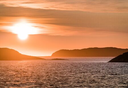 Beautiful Sunset with mountains and icebergs. Arctic circle and ocean. Sunrise horizon with pink sky during midnight sun. Photo taken in Greenland.の写真素材