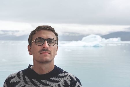 Happy and smiling young man standing in front of Eqip Sermia glacier called Eqi Glacier. Tourist...