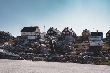 Aerial View of Arctic city of Ilulissat, Greenland. Colorful houses in the center of the town with icebergs in the background in summer on a sunny day with blue sky and cloudsの写真素材