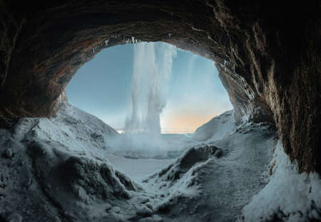 View of Seljalandsfoss waterfall at dawn in winter in Iceland with snow and frozen ice in the...