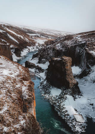 Aerial Drone view of Fjadrargljufur canyon and Fjadra river at winter. White snow and blue river....