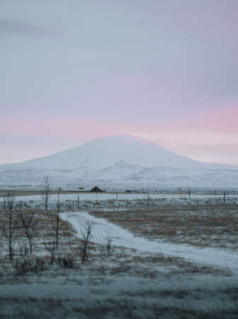 Landscape view of Hekla volcano in South iceland during Winter sunset with snow and fluffy pink clouds.の写真素材
