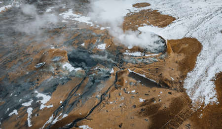 Aerial Drone panorama with hot steam coming from the ground. Hverir is geothermal area in Myvatn. Landscape covered with snow and orange ground.の写真素材