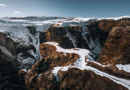 Aerial Drone view of Fjadrargljufur canyon and Fjadra river at winter. White snow and blue river....