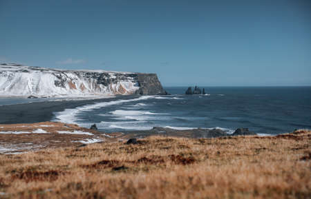Dramatic winter landscape of Icelandic Black Sand Beach Reynisfjara near town Vik. Stormy sea shore...