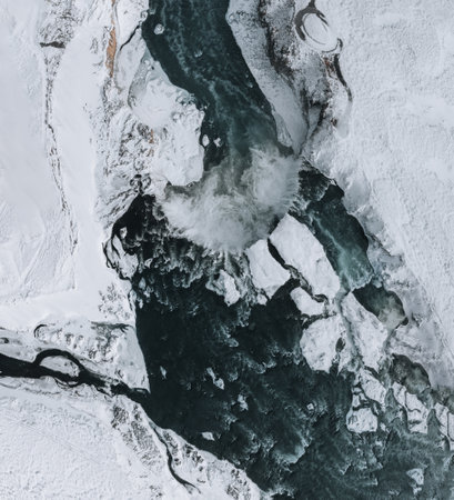 Drone shot of Godafoss waterfall, Iceland, taken from a high angle. Aerial view of the powerful cascade, river and snow covered rocks. Late autumn, early winter scene.の写真素材