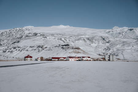 Iceland winter landspace with traditional farm house and fjord and mountain covered in snow. Blue...