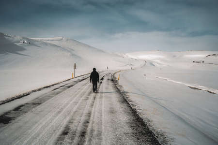 Man walking in high fresh snow leaving footsteps. Perfect winter day with blue sky and sun. Winter sports and hiking concept. Photo taken in Iceland near Akureyri and Myvatn.の写真素材