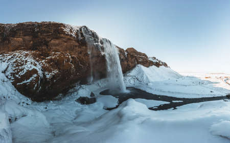 Seljalandsfoss waterfall in Iceland during winter with blue sky and snow and frozen landscape.の写真素材