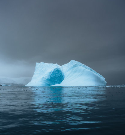 Photogenic and intricate iceberg with a hole under an interesting and colorful sky during. Global warming and climate change concept. Photo taken in Antarctica, Greenland arctic circle.の写真素材
