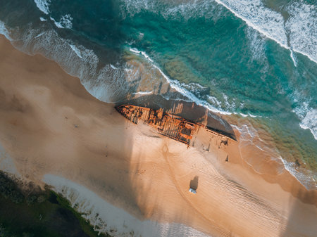 Kgari High angle aerial birds eye drone view of the Maheno shipwreck on Seventy-Five Mile Beach on Fraser Island, Queensland, Australia. Beautiful sunset light with waves.の写真素材