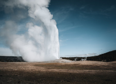 Errupting Old Faithful Geyser in Yellowstone National Park, Wyoming, USA. Travel and adventure concept. Blue sky and sunny day.の写真素材