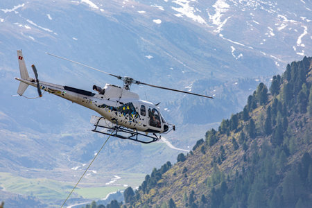 Close-up of a helicopter flying over the forest with attached transportastion rope in swiss alps