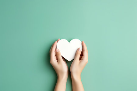 two hands over a gree lay flat holding a white heartの素材
