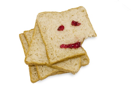 Eating happy face jam on whole wheet bread on white background