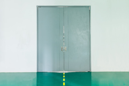 Grey heavy metal door on white wall in buildingの写真素材
