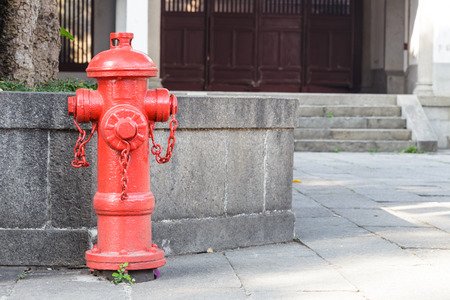 Red fireplug standing on footpath for fire fightingの写真素材