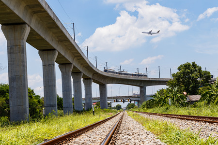 Airplane over skytrain and train near airportの写真素材