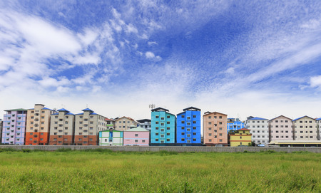 Row of houses and apartments behide grass field and sky