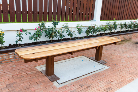 Wooden bench on footpath near wall