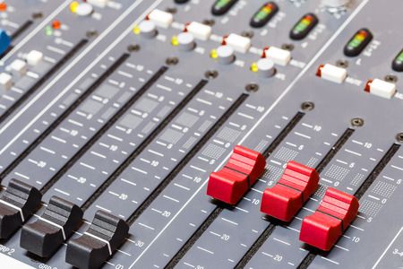 Closeup on red sliders of sound mixing console in audio recording studio
