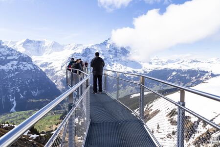 GRINDELWALD BERNE, SWITZERLAND- APRIL 24, 2018 : Traveller are resting and photograph on sky cliff walk at First peak of Alps mountain Grindelwald Switzerlandの写真素材