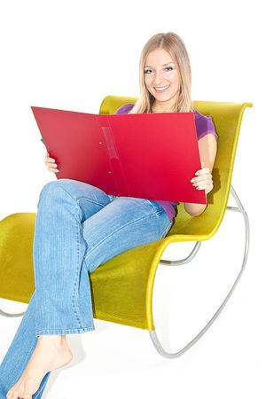 Woman sitting on green chair writing in open fileの写真素材