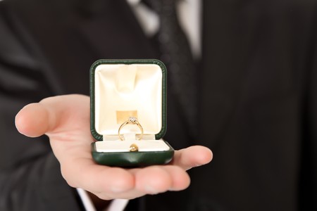 Man in suit holding engagement ring on white isolated background