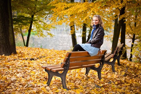 Young caucasian student girl in golden autumn parkの写真素材