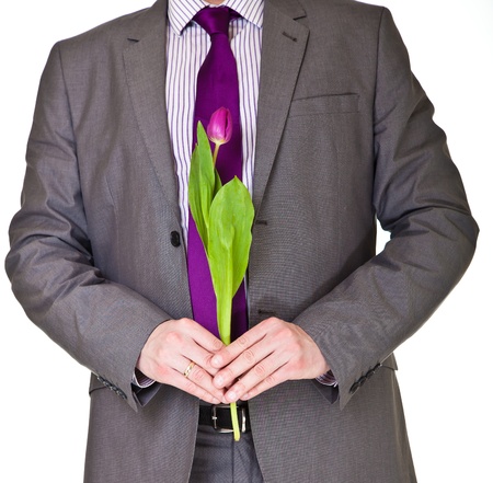 Man in suit and tie holding tulip flower isolated on whiteの写真素材