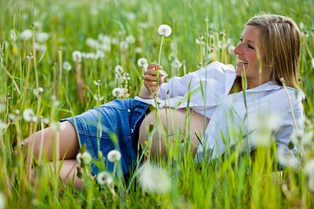 Pregnant woman sitting on green fieldの写真素材