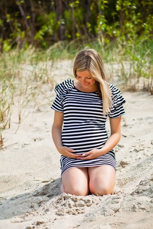 Pregnant woman sitting on green fieldの写真素材