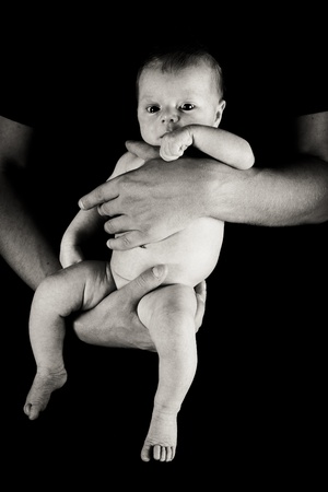 Infant girl on fathers arms isolated on blackの写真素材