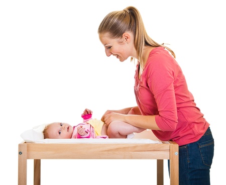 Mother changing little girl's diaper on nursery table の写真素材