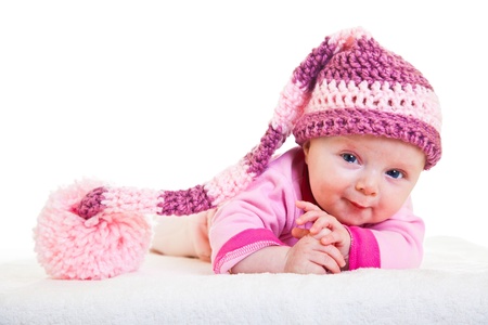 Infant baby girl raising head in funny hat isolated on whiteの写真素材