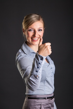 Businesswoman thumbs up on gray backgroundの写真素材