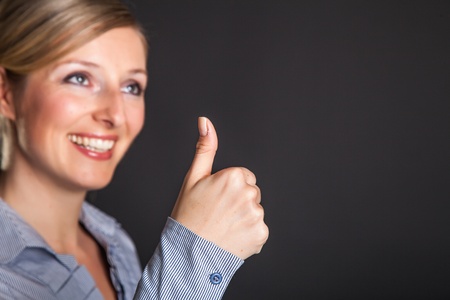 Businesswoman thumbs up on gray backgroundの写真素材