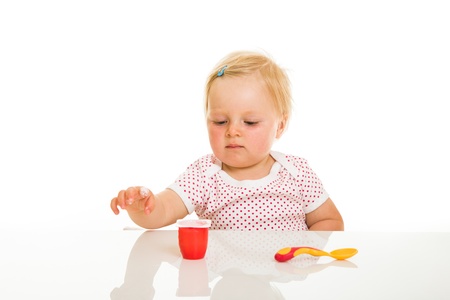 Cute infant girl learining to eat with spoonの写真素材