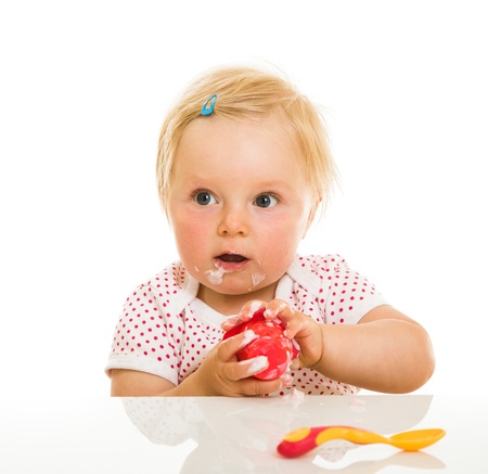 Cute infant girl learining to eat with spoonの写真素材