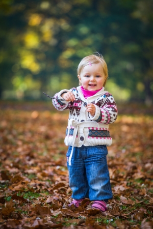 Infant baby girl in golden autumn parkの写真素材