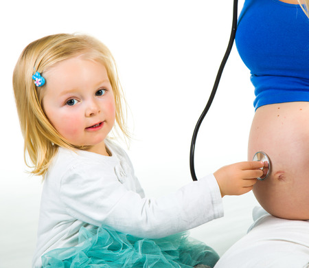 Pregnant woman with 2 zo daughter on whiteの写真素材